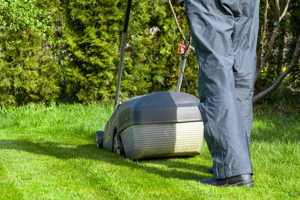 Man mowing with lawn mower in the garden, gardening concept