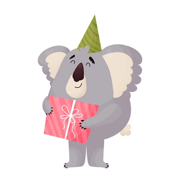 Cute cheerful Koala in a festive cap holds a gift. Vector cute animal in cartoon style . — Stockvector