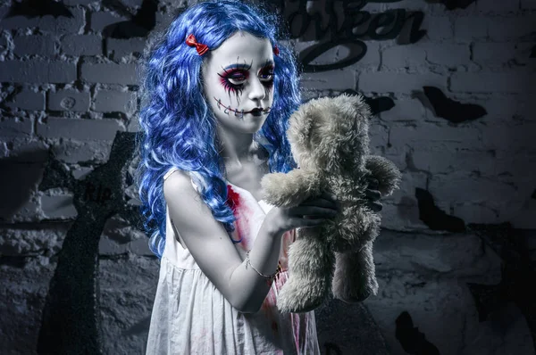 Pequeña chica de pelo azul en vestido sangriento con el maquillaje de Halloween miedo con oso de peluche — Foto de Stock