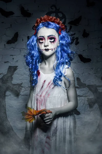 Pequena menina de cabelo azul com maquiagem assustadora halloween está segurando folha amarela Fotos De Bancos De Imagens