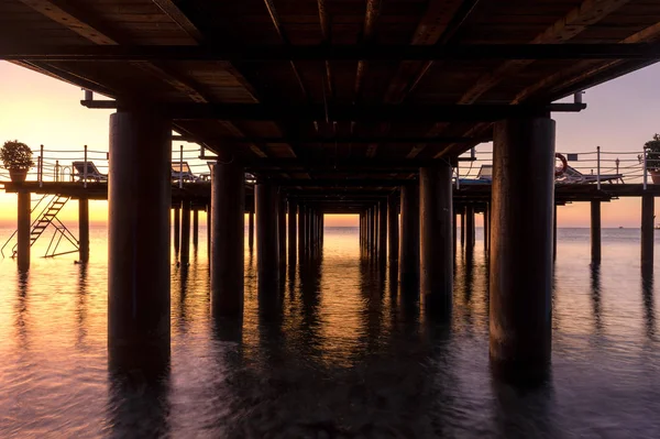 Foto del amanecer del mar entre las columnas del muelle — Foto de Stock