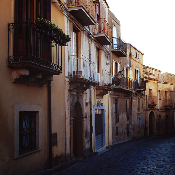 Via Roma. Paved street in the mediterranean city of Enna. Autumn evening. Houses of downtown main street. Aged photo. Sicily, Italy.