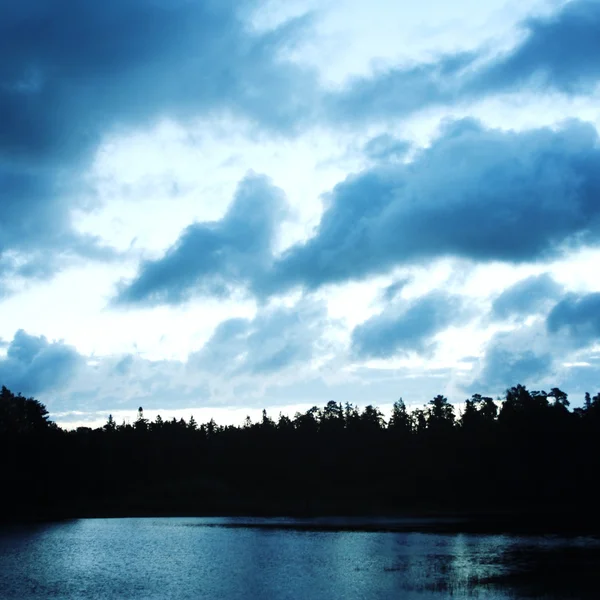 Облачное небо на закате. Силуэт озера и леса . — стоковое фото