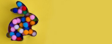 Tavşan şekilli zencefilli çörek, sarı arka planda renkli toplar. Paskalya konsepti. Metin için yeri olan Bunner.