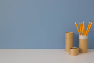 Mavi arka planda sarı kalemli kağıt tüpler. Evdeki kağıt tüplerin nasıl yeniden kullanılacağını gösteren geri dönüşüm konsepti. Boşluğu kopyala