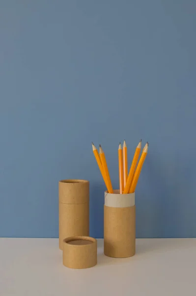 Paper tubes with yellow pencils on blue background. Recycle concept showing how to reuse paper tubes at home. Copy space. Vertical photo