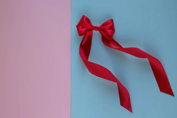 ピンクの背景にコピースペースのある青の背景にシルクリボンで作られた明るい赤い弓。お祭り騒ぎだ誕生日の挨拶の概念。閉じろ!. — ストック写真
