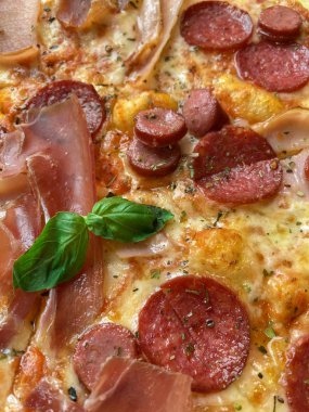 Sıcak İtalyan pizzasına yaklaş. Üzerine salam, peynir, kızarmış jambon ve taze yeşil fesleğen ekilmiş mayalı ekmek. Kapatın. Dikey mobil fotoğraf
