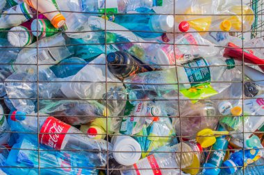LVIV, UKRAINE - 26 Mart 2020: endüstri geri dönüşüm kavramı. Ekolojik tedaviler üzerine uzmanlaşmış bir şirketin bahçesinde geri dönüşüm için metal çöp kutusunda büyük miktarda plastik şişe ve konteynır var.