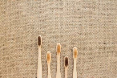Doğal bambu diş fırçaları seti üzerinde, arka planda, fotokopi alanı olan kabarık çuval bezleri. Sürdürülebilir yaşam tarzı ve plastik içermeyen konsept, sıfır atık ev. Banyo gereksinimleri.