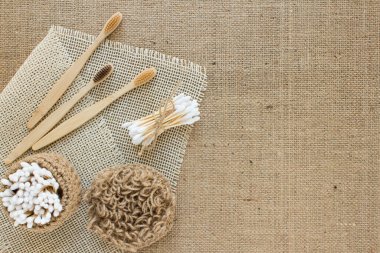 Doğal banyo gereksinimleri seti. Sürdürülebilir sıfır atık kavramı. Diş fırçaları, bambu çubukları, çamaşır yıkamak için jüt bezi ya da fotokopi alanı olan kumaş arka planında kuru anti-selülit masajı.