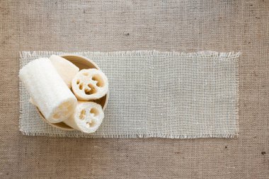 Doğal kumaş arka planında doğal luffa süngeri. Uzayı kopyala, çevre dostu kavram. Bulaşık ya da banyo için kullan