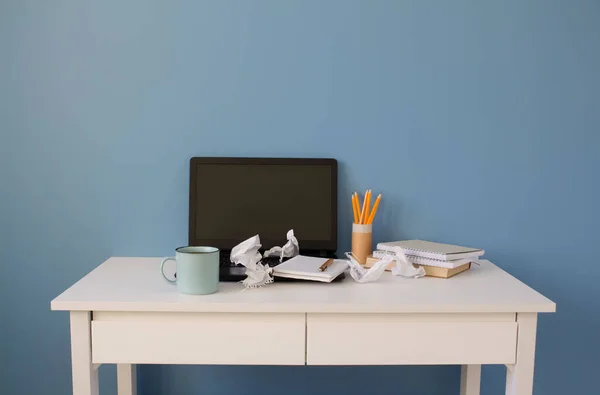 Empty home office of creative entrepreneur with black laptop on white table during lunch break. Modern workspace with blue cup of coffee and yellow pencils in paper tube as reusable packaging concept. — Stock Photo, Image