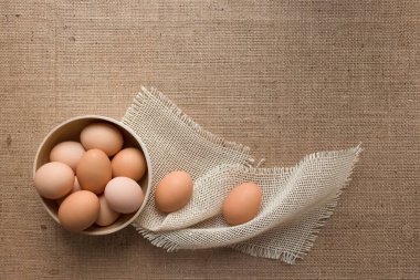 Yerel çiftçi pazarından taze organik tavuk yumurtalarının üst görüntüsü keten masa örtüsü üzerinde ahşap bir kâse içinde metin için fotokopi alanı, seçici odaklanma