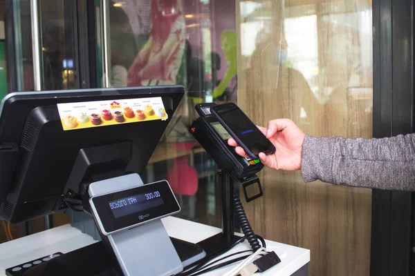 Lviv, Ukrayna - 17 Mayıs 2020: McDonalds restoranı, müşteri NFC teknolojisini kullanarak ödemeyi akıllı telefonla yapıyor. İrtibatsız ve sosyal uzaklık konsepti, işletmeyi yeniden açmak