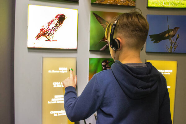 Vyhoda, Dolyna district, Ukraine - January 25, 2020 : Vyhoda Narrow Gauge Railway Heritage Center, boy playing using interactive stand for listening information about birds. Local tourism concept