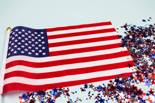 Closeup of american flag and stars shaped sparkles on light blue background with copyspace. National symbolic of USA - flag Old Glory. Independence Day, Memorial Day and Flag Day celebration concept