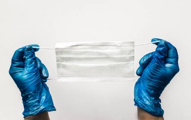 Mavi eldivenler ve enfeksiyon ve virüslere karşı koruyucu bir maske. Coronavirus yüzleşmesi.