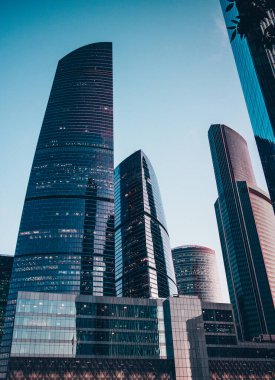 Yüksek gökdelenlerin manzarası. Mavi gökyüzü arka planında gökdelenler. Yüksek bina. Şehrin iş merkezi. Modern şehir mimarisi. Cam ve beton evler..