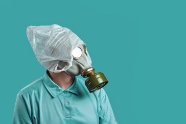 Gaz maskeli bir adam ve kafasında plastik bir torba nane arkaplanındaki kirliliğe karşı çevrenin korunmasını simgeler.