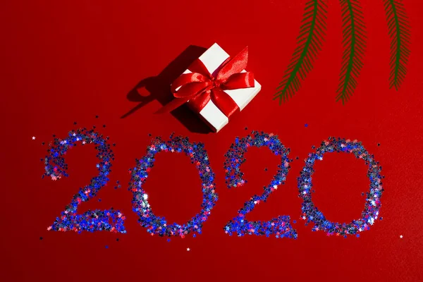Boîte cadeau blanche avec ruban rouge, chiffres de l'année prochaine, bordée d'étoiles sur fond rouge — Photo