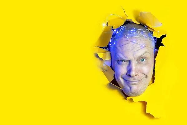 Hombre sorprendido mirando a través del agujero en papel amarillo. Copiar espacio para publicidad — Foto de Stock