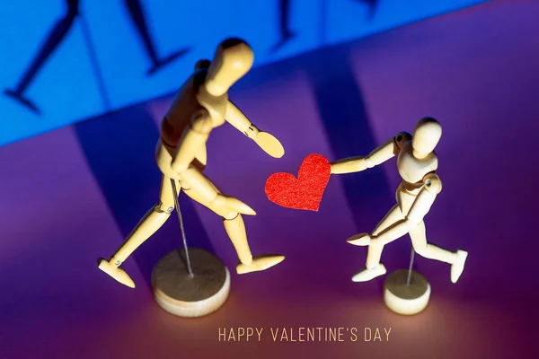 Dos hombres de madera sostienen sus corazones en sus manos. Sobre un fondo azul — Foto de Stock