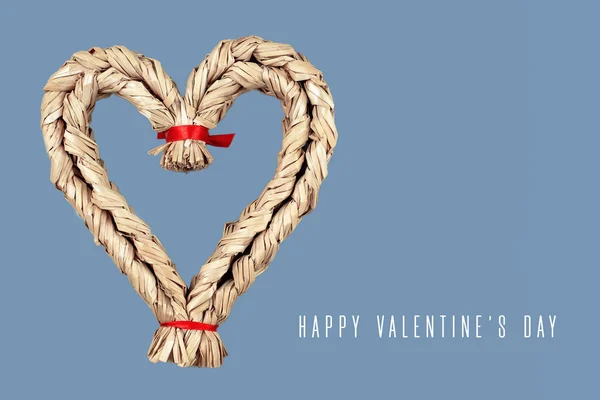 Straw heart with red ribbons on a gray background. The concept for Valentine's Day — Stock Photo, Image