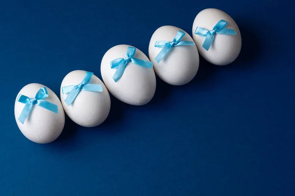 Drei Ostereier mit Schleifen auf blauem Grund. Osterkonzept — Stockfoto