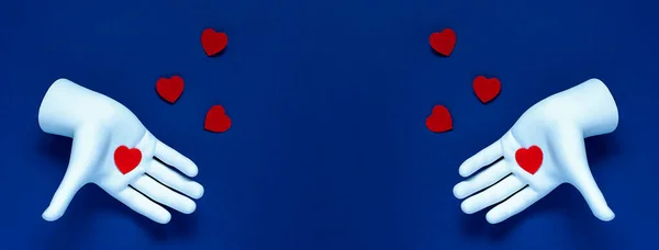 Dos manos lanzan corazones rojos sobre un fondo azul. El concepto para el Día de San Valentín — Foto de Stock