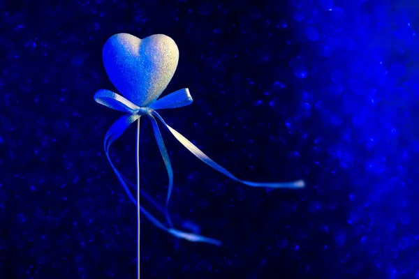 Un corazón con un arco. Azul borroso bokeh en el fondo. El concepto para el Día de San Valentín — Foto de Stock