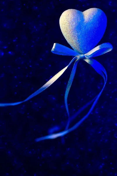 Un corazón con un arco. Azul borroso bokeh en el fondo. El concepto para el Día de San Valentín — Foto de Stock