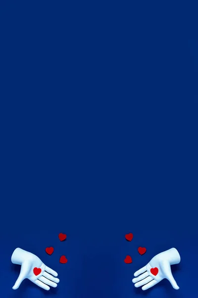 Dos manos lanzan corazones rojos sobre un fondo azul. El concepto para el Día de San Valentín —  Fotos de Stock