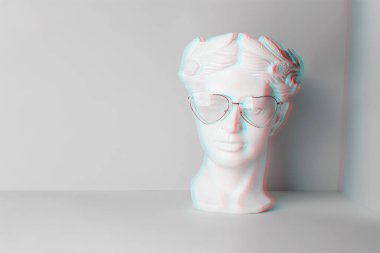 Kalpli, pembe gözlüklü, antika bir kafa heykeli. İki rengin geometrik arka planında