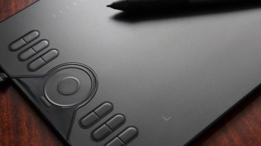 black graphic tablet with pen on table