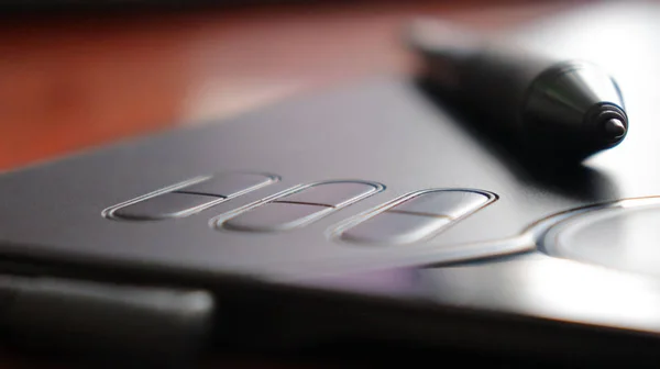 Black graphic tablet with pen on table — Stockfoto