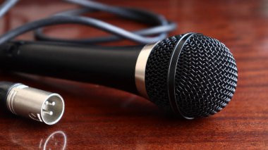 Klor kablosu olan siyah mikrofon ahşap yüzeyde, ses ekipmanı var.