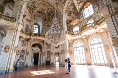 Torino, Italy - April 25 2018: tourists marvel at the grand interiors of main hall of UNESCO World Heritage Palazzina di Caccia of Stupinigi, Savoy royal hunting lodge designed by architect Juvarra