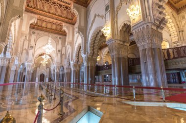 Casablanca, Morocco - April 2019: Interior (prayer hall) of Hassan II Mosque with columns, arches and glass chandeliers. The building blends Islamic architecture and Moroccan elements