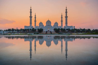 Abu Dhabi, UAE, United Arab Emirates: Stunning view of Abu Dhabi Sheikh Zayed Mosque (also known as Grand Mosque) at dusk, reflection in water, illuminated at sunset, golden blue hour