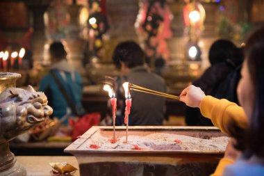 Sheung Wan, Hong Kong - Ocak 12018: Bir kadın ünlü Man Mo tapınağında mum yakarken tütsü yakar.