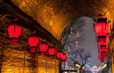 Xian, China - January 2018: Red lanterns and the Bell Tower of Xian illuminated by night seen from the North Gate during Christmas season with snow, Xmas decorations and Christmas lights.