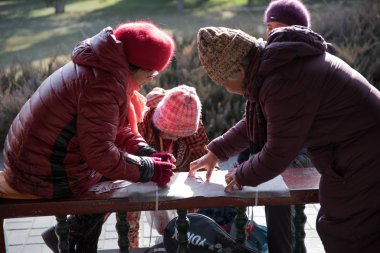 Pekin, Çin - 6 Ocak 2018: Çinli yaşlı kadınlar soğuk bir kış günü Temple of Heaven Park 'ta Çin' de yaşlılar için geleneksel bir oyun olan kart oynuyorlar.