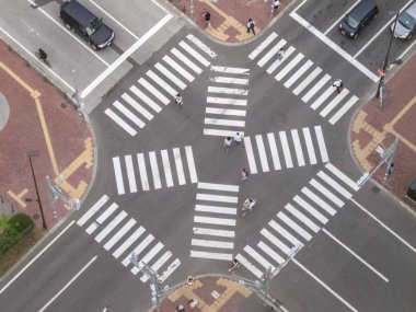 Sapporo, Hokkaido, Japan - August 2015: Aerial view of Japanese crosswalk (pedestrian crossing) with people, bikers and cars crossing, view from above (from the Sapporo TV tower observation deck)