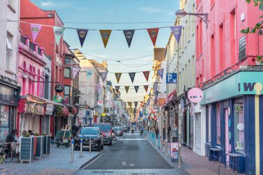 Cork, Ireland  September 2019: Beautiful view of Oliver Plunkett Street, city center, traditional colorful Irish houses, ensigns, triangular flags, banners, people tourists strolling walking