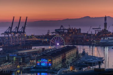 Genoa (Genova), Italy - December 2018: Sunset aerial panoramic view of port, Lanterna (lighthouse symbol of the city), Porto Antico, Magazzini del Cotone, Ferris wheel and dockside container cranes.