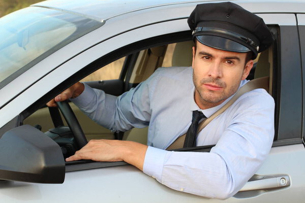 Taxi driver in cap sitting in car