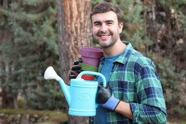 Bahçesinde boş tencereleri olan yakışıklı bir gencin yakın plan portresi.