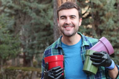 Bahçesinde boş tencereleri olan yakışıklı bir gencin yakın plan portresi.