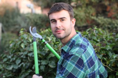 Bahçede çalıları kesen yakışıklı genç adamın yakın plan portresi.